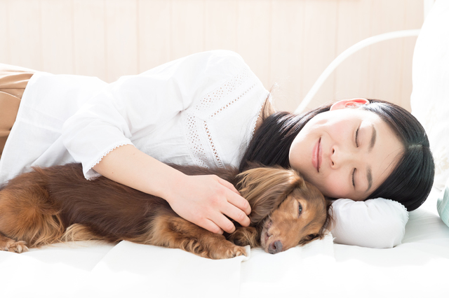 犬と一緒に寝る女性