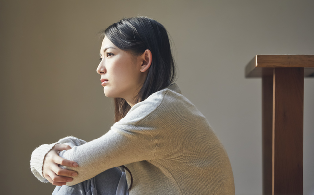膝を抱えて座る女性