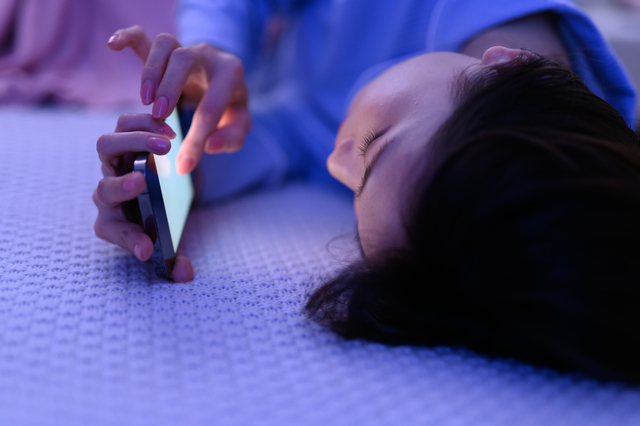 寝ながらスマホを操作する女性