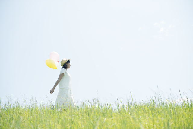 風船を持って草原を歩く女性