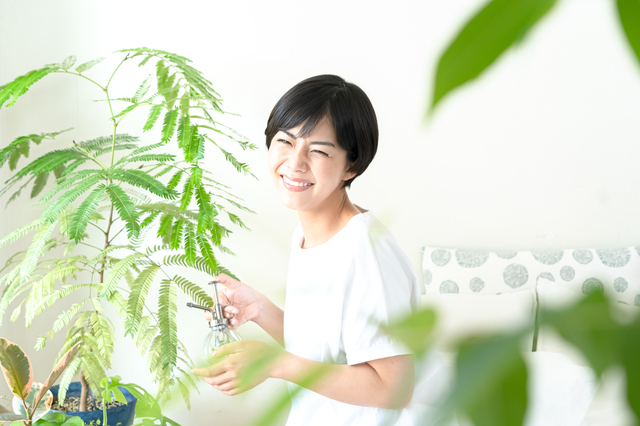 観葉植物に囲まれて笑顔の女性