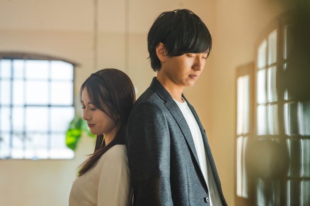 背中合わせに寄り添って目を閉じる男女
