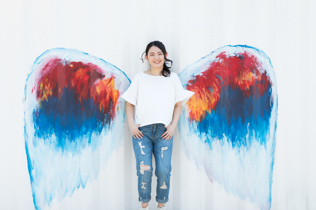 天使の羽の壁画の前で写真を撮る女性