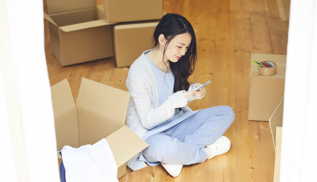 引っ越し中にスマホで調べる女性