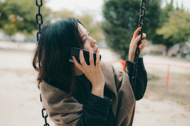 公園で電話占いをする女性