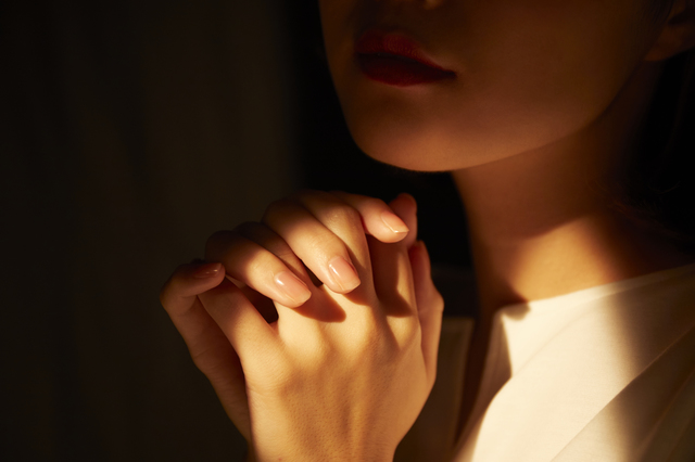 祈るポーズをする女性