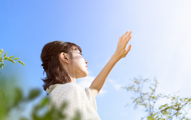 日光を浴びて目を閉じる女性