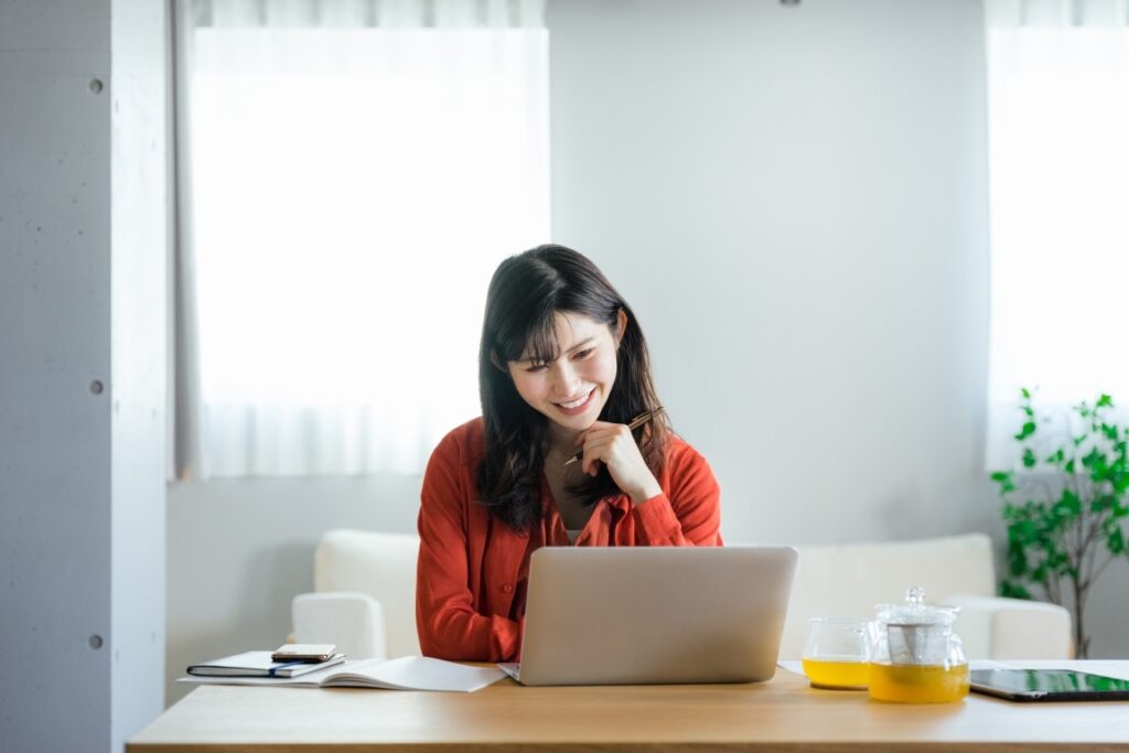 リビングでノートパソコンを使ってオンラインで資格の勉強をしながら考える20代から30代の日本人の女性