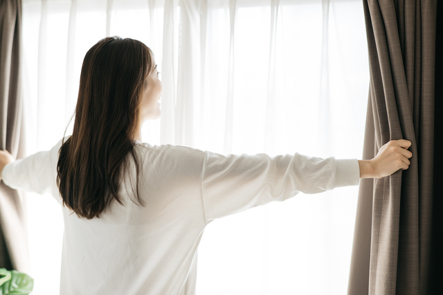 カーテンを開ける女性　寝起き