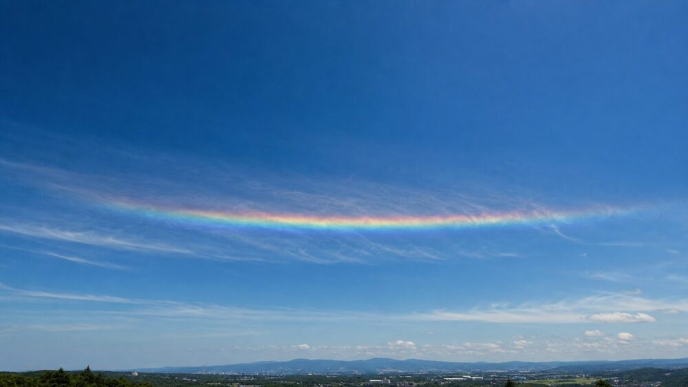 青空の太陽より下に横長の虹色の帯として現れた環水平アーク